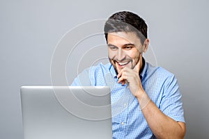 Portrait of young smiling man sitting at the desk with laptop