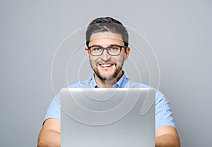 Portrait of young smiling man sitting at the desk with laptop