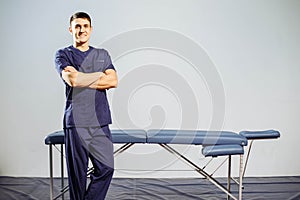 Portrait of young smiling man in uniforme near massage couches. photo