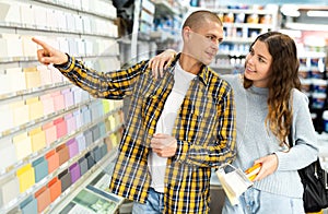 Portrait of young smiling man and woman choosing color for wall painting