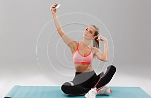 Portrait of a young smiling sportsgirl taking selfie