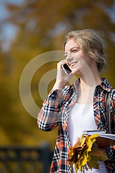 Portrait of a young smiling student outsides, talking on phone