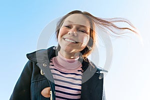 Portrait of a young smiling teen girl, background blue sky