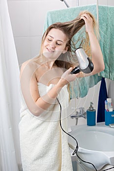 Portrait of young smiling woman drying long hair after having bath