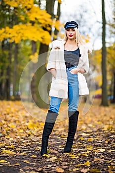 Portrait of young smiling woman with hair, dressed in coat near branches of a tree with yellow foliage for a walk in the park. Por