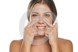 Portrait of young smiling woman touches her nose