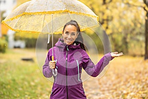 Portrait of a young smiling woman under an umbrella on a walk in the autumn park