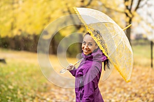 Portrait of a young smiling woman under an umbrella on a walk in the autumn park