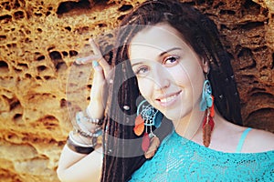 Portrait of a young smiling woman wearing dreadlocks hairstyle, dressed in blue lace dress and blue boho chic earrings