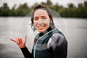 Portrait of young smiling woman with wet hair in swimwear who shows hand gesture.