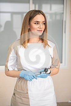 Portrait of Young specialist woman dermatologist with dermatoscope in uniform and gloves in doctor office, examination