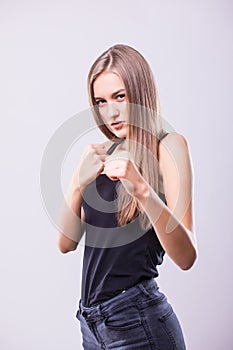Portrait of young sport girl training boxing against grey background.