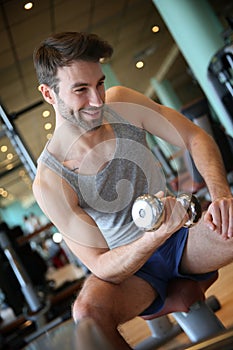 Portrait of a young sportive man lifting weights