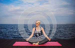 A portrait of young sportswoman doing yoga exercise on beach. Copy space.