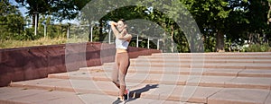 Portrait of young sportswoman running on street. Fitness girl jogging in park, workout outdoors, listening music in
