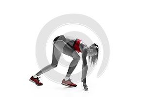 Portrait of young sporty woman at starting block of race isolated over white background