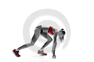 Portrait of young sporty woman at starting block of race isolated over white background