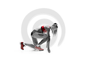 Portrait of young sporty woman at starting block of race isolated over white background