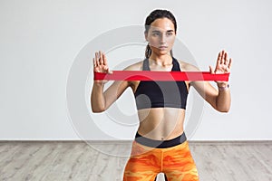 Portrait of young sporty woman wearing black top and orange leggings performs exercises for the muscles of the hands, workout with