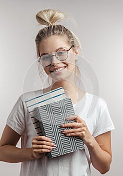 Portrait of young student girl with books isolated over grey wall background