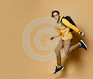 Portrait of a young student man jumping in the studio on a beige background