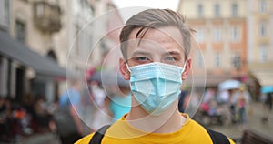 Portrait of a young student man wearing a protective mask on the street, wearing a ovid-19 mask. Health and safety