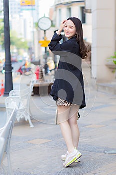 Portrait of young stylish hipster business beautiful Asian woman is walking on the street, wearing cute trendy outfit, turn behind