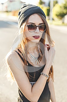 Portrait of a young stylish hipster girl dressed in dark cap and sunglasses