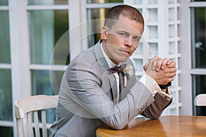 Portrait of a young stylish man in a classic business suit in gray with a white shirt and a bow tie. A young guy is a
