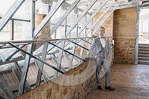 Portrait of a young stylish man in a classic business suit in gray with a white shirt and a bow tie. A young guy is a