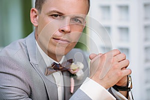 Portrait of a young stylish man in a classic business suit in gray with a white shirt and a bow tie. A young guy is a