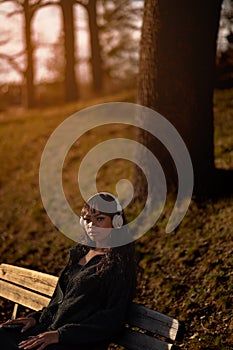 Portrait of young stylish woman with headphones outside