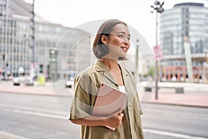 Portrait of young stylish woman walking with tablet, going somewhere in city