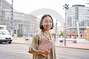 Portrait of young stylish woman walking with tablet, going somewhere in city