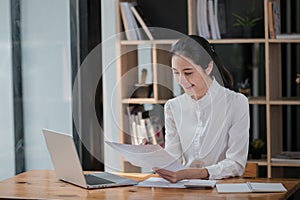 Portrait of Young Successful Asian Businesswoman Sitting at Desk Working on Laptop Computer in Office. Ambitious