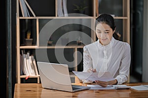Portrait of Young Successful Asian Businesswoman Sitting at Desk Working on Laptop Computer in Office. Ambitious