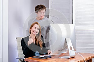 Portrait of young successful woman and man at office. They look at the display approvingly. Black Friday or Cyber Monday. Browsing