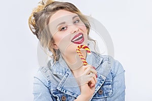 Portrait of Young Surprised Caucasian Blond Girl Eating Big Red-Yellow Candy Cane