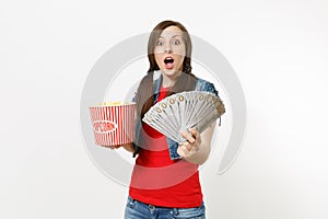 Portrait of young surprised pretty woman in casual clothes watching movie film, holding bucket of popcorn and bundle of