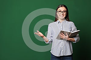 Portrait of young teacher with book on green background