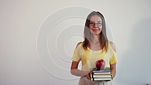 Portrait of young teacher on white background. Girl with stack of books and apple on top.