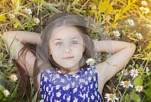 Portrait of a young teen girl happy lying in daisies
