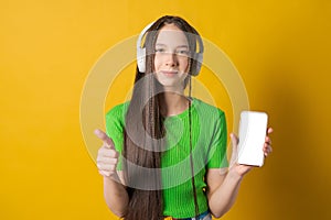 Portrait young teen girl posing isolated over yellow background wall listening