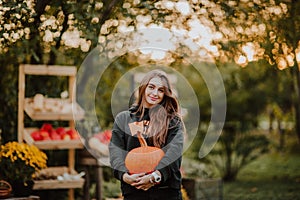 Portrait of young teen girl posing with pumpkins on a farm. Copy space