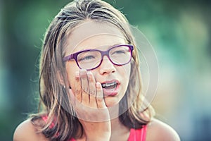 Portrait of young teen girl with toothache. Girl with dental braces and glasses