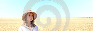 Portrait of Young teenage girl standing in a wheat field over blue sky background.