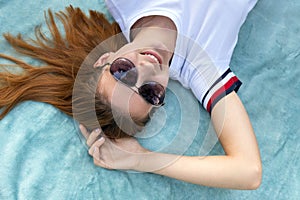 Portrait of young teenage girl in sunglasses laying down on blue cloth background