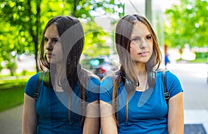 Portrait of young teenager brunette girl with long hair. an urban environment of a street warehouse, woman and reflection in the g