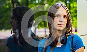Portrait of young teenager brunette girl with long hair. an urban environment of a street warehouse, woman and reflection in the g