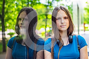 Portrait of young teenager brunette girl with long hair. an urban environment of a street warehouse, woman and reflection in the g